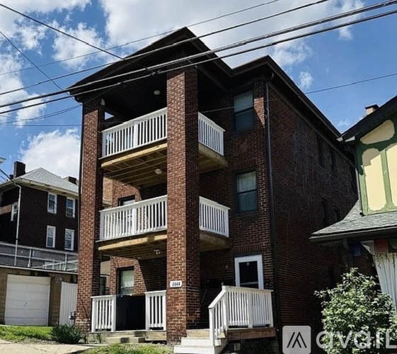 A red brick building with a balcony in front.