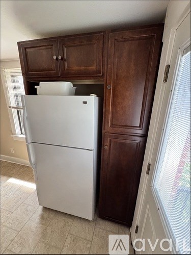 A white refrigerator sits next to a brown cabinet in a kitchen.
