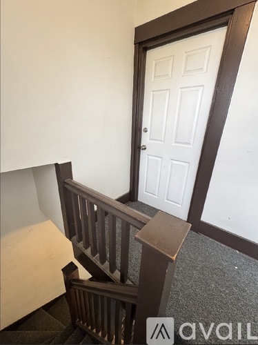 A white door is in a room with a brown staircase.