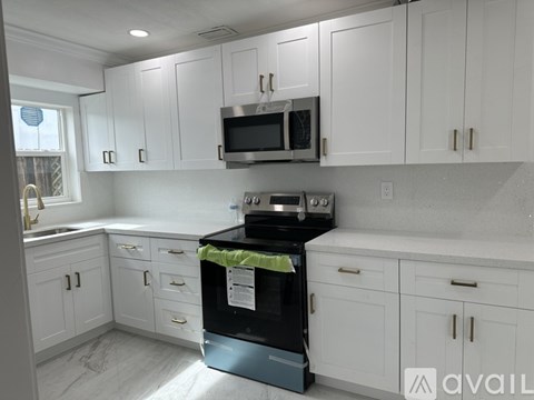 A kitchen with white cabinets and a black stove top oven.