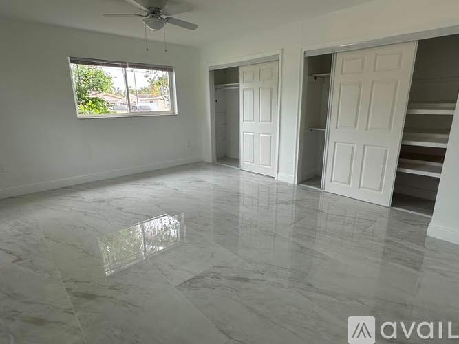 A spacious room with a marble floor and a ceiling fan.
