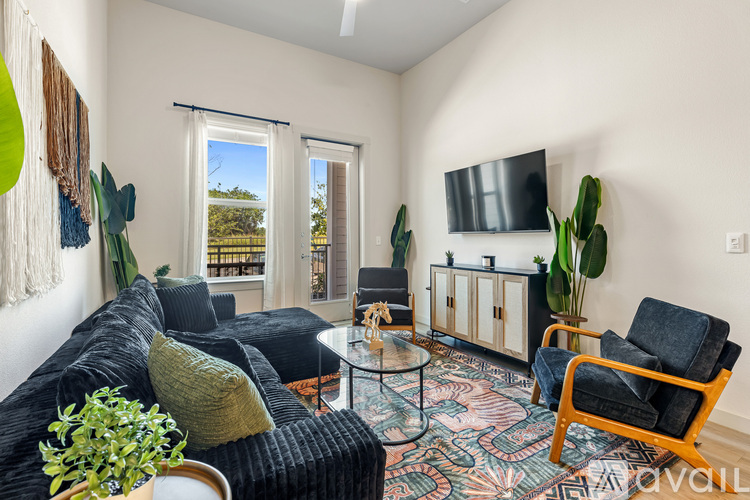 A living room with a black couch and a glass coffee table.