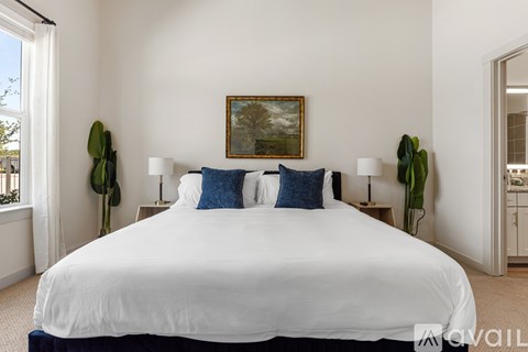 A bedroom with a large bed and a painting on the wall.