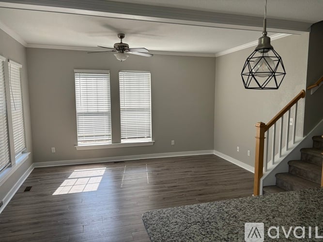 A room with a ceiling fan and a staircase.