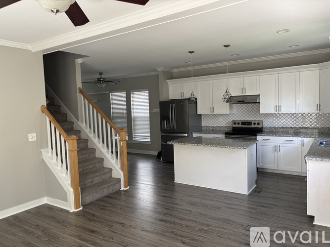 A kitchen with white cabinets and a staircase with wooden railings.