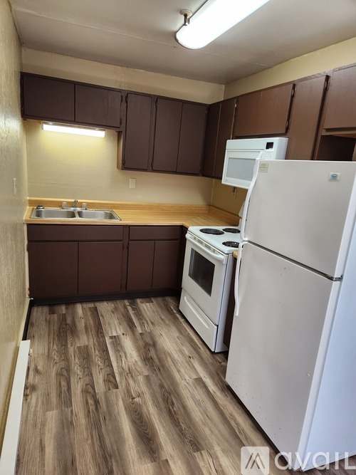 A kitchen with brown cabinets and a white refrigerator.