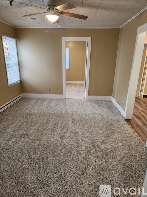 A room with a carpeted floor and a ceiling fan.