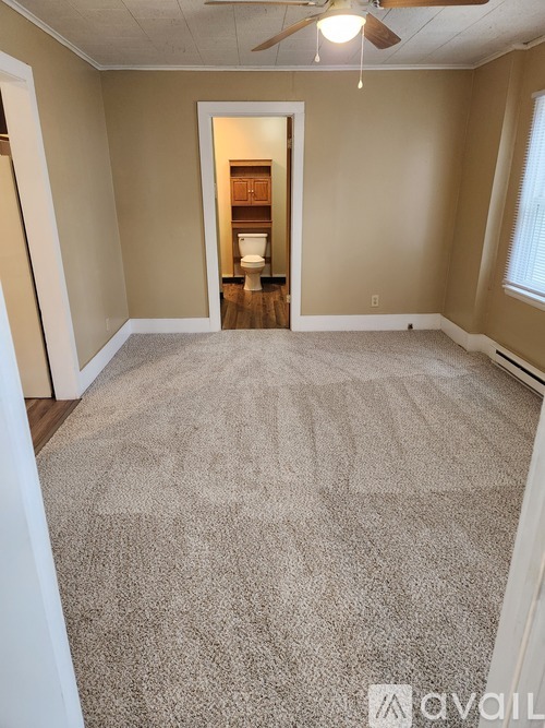 A room with a carpeted floor and a ceiling fan.