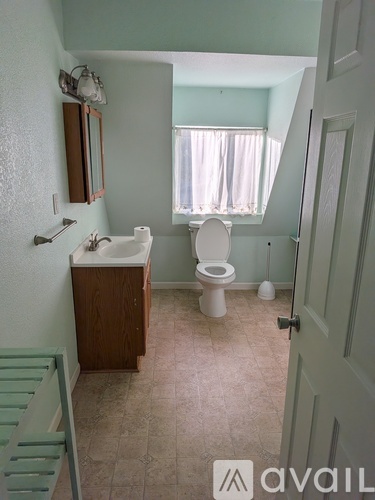 A bathroom with a toilet, sink, and mirror.