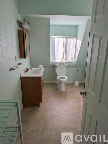 A bathroom with a toilet, sink, and mirror.