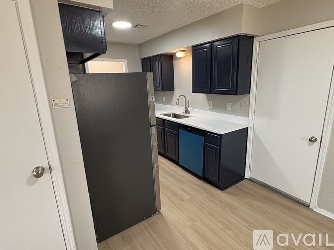 A kitchen with black cabinets and a white refrigerator.