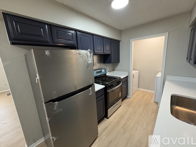 A kitchen with a stainless steel refrigerator, black cabinets, and a white countertop.