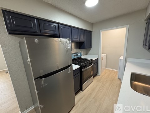 A kitchen with a stainless steel refrigerator, black cabinets, and a white countertop.