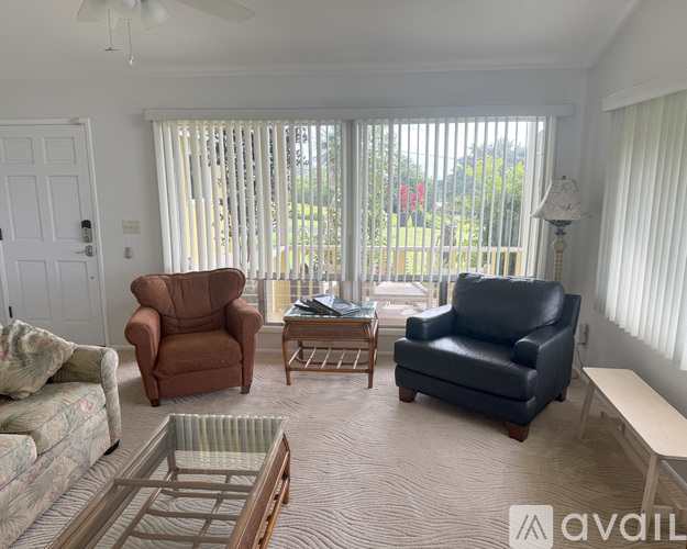 A living room with a brown and black leather sofa, a wooden coffee table, and a glass table with a metal frame.
