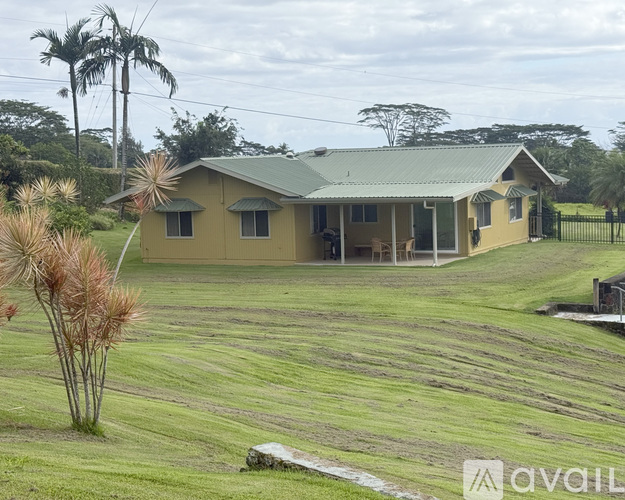 A house with a green roof is surrounded by a grassy field.