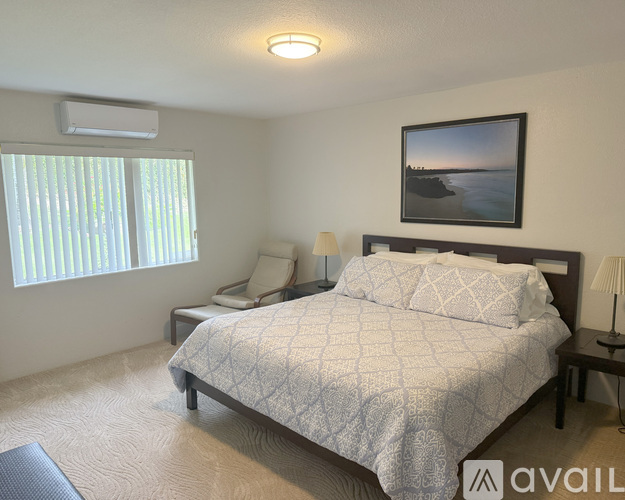 A bedroom with a large bed and a picture on the wall.