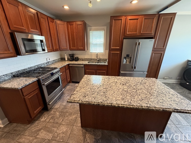 A kitchen with brown cabinets and granite countertops.