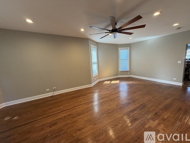 A spacious room with wooden flooring and a ceiling fan.