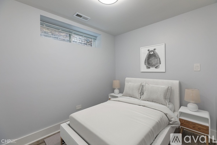 A bedroom with a white bed and a picture of a bear on the wall.