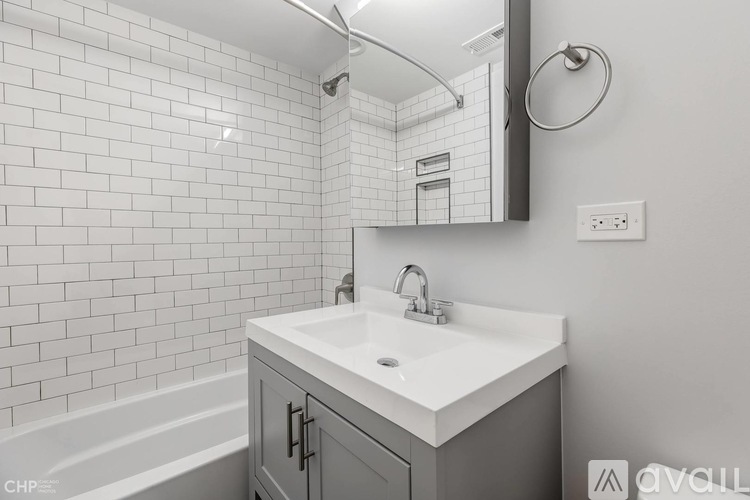 A white sink in a bathroom with a grey cabinet.