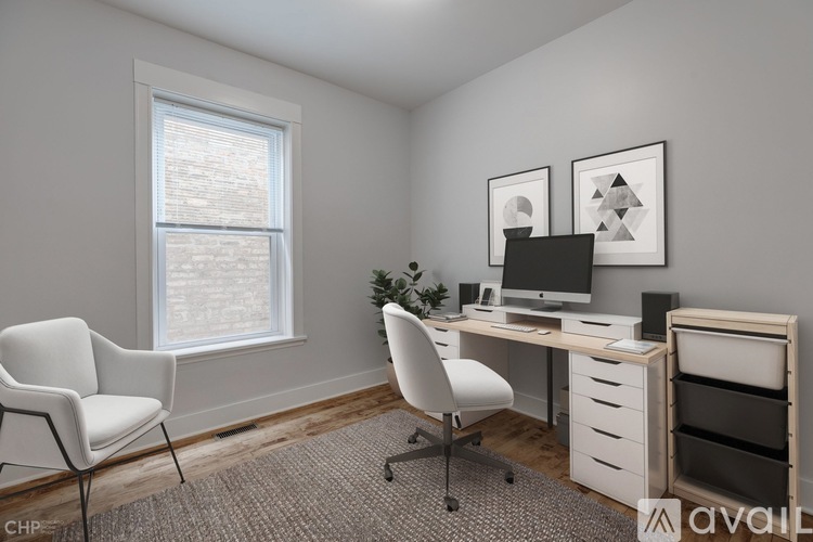A white chair is in front of a desk with a computer monitor and keyboard.
