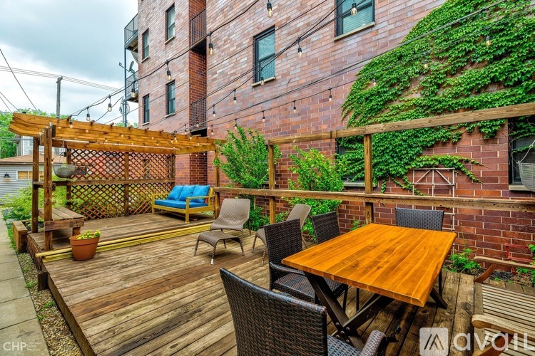 A wooden deck with a table and chairs is surrounded by a brick building.