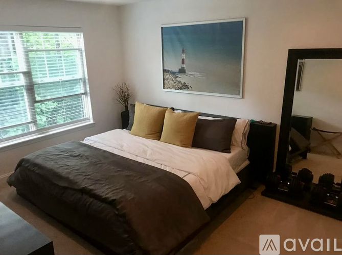A bedroom with a large bed and a painting of a lighthouse on the wall.