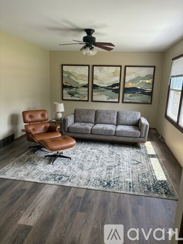 A living room with a grey couch, a brown leather chair, and a rug.