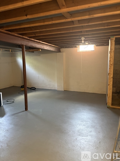 A spacious, unfinished room with a concrete floor and exposed wooden beams.