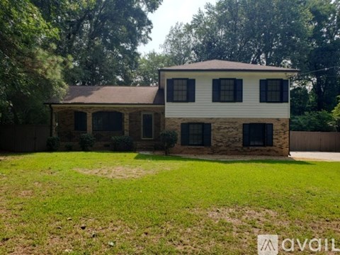 A house with a white and brown exterior is surrounded by greenery.