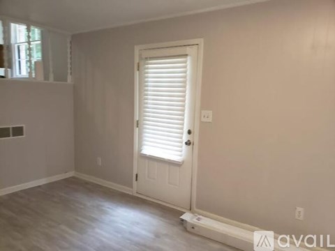 A room with a white door and a window with blinds.