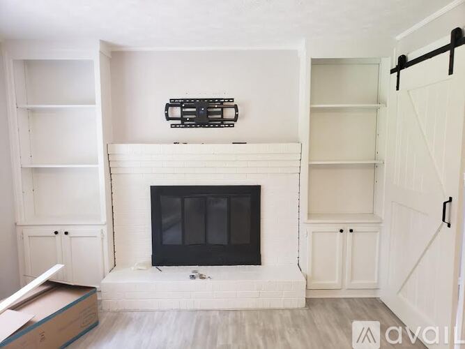 A white fireplace with a black screen in a room with white walls.