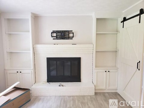 A white fireplace with a black screen in a room with white walls.