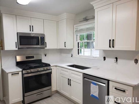 A kitchen with white cabinets and appliances.