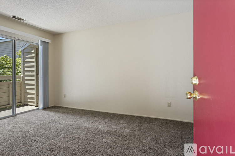 A room with a carpeted floor and a red door.