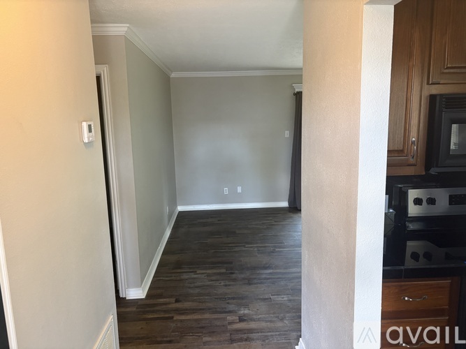 A room with wooden floors and a white wall with a switch.
