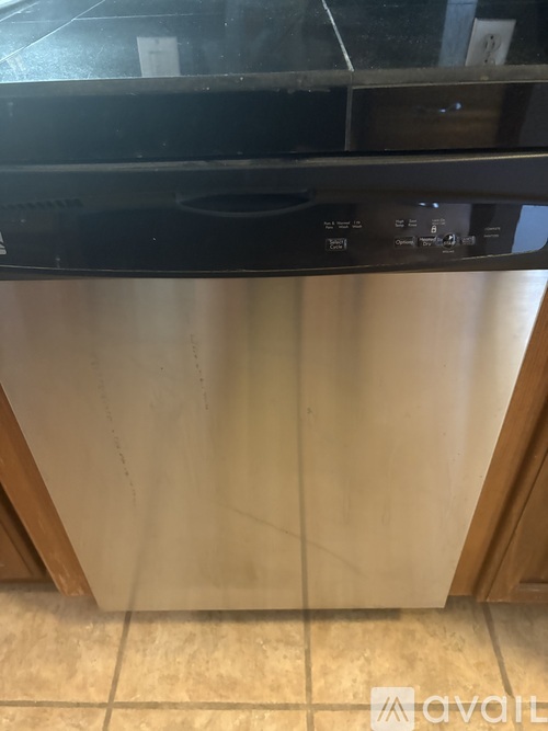 A stainless steel dishwasher with a black top is in a kitchen.