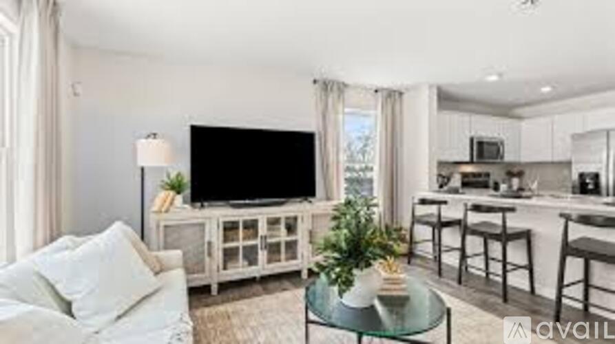A living room with a white couch and a glass coffee table.