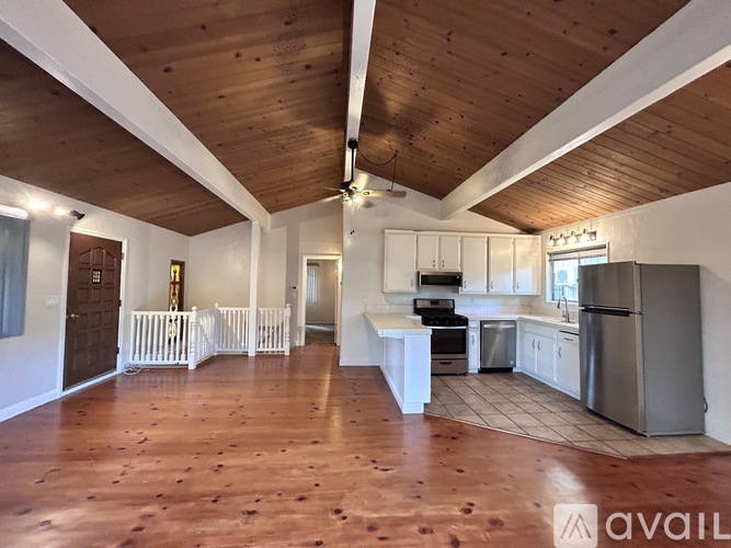 A spacious kitchen with wooden floors and white cabinets.