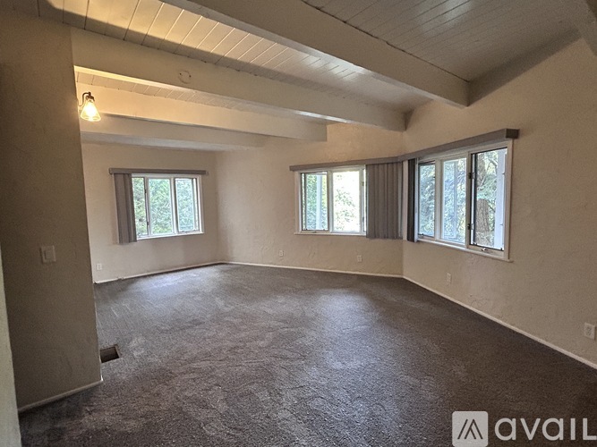 A spacious room with a carpeted floor and large windows.