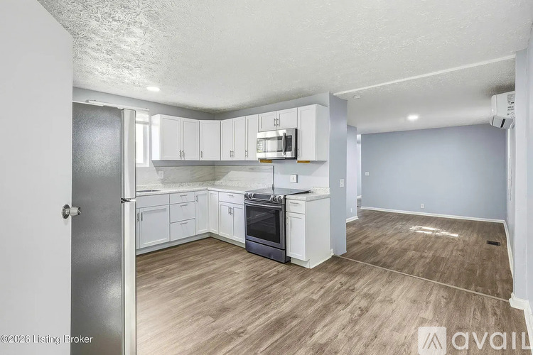A kitchen with white cabinets and a wooden floor.