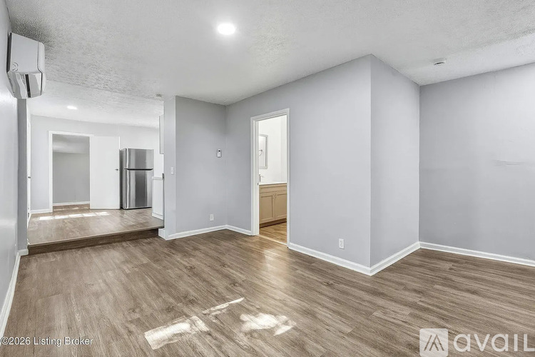 A spacious room with wood flooring and white walls is available for rent.