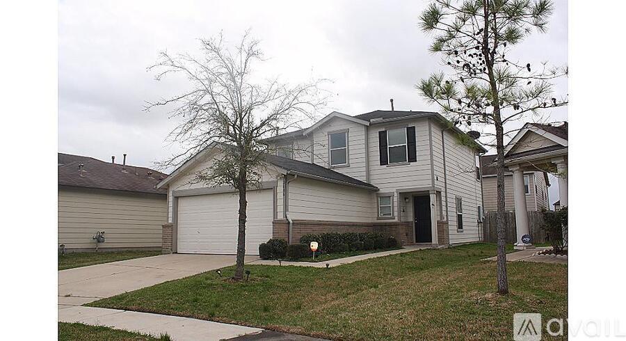 A house with a driveway and a tree in front.