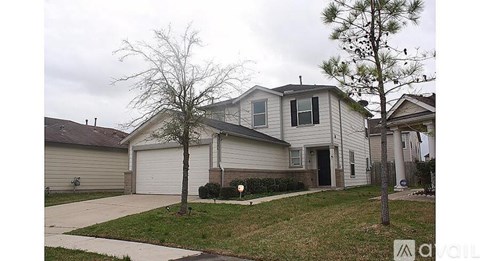A house with a driveway and a tree in front.