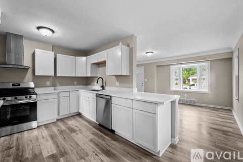 A kitchen with white cabinets and a wooden floor.