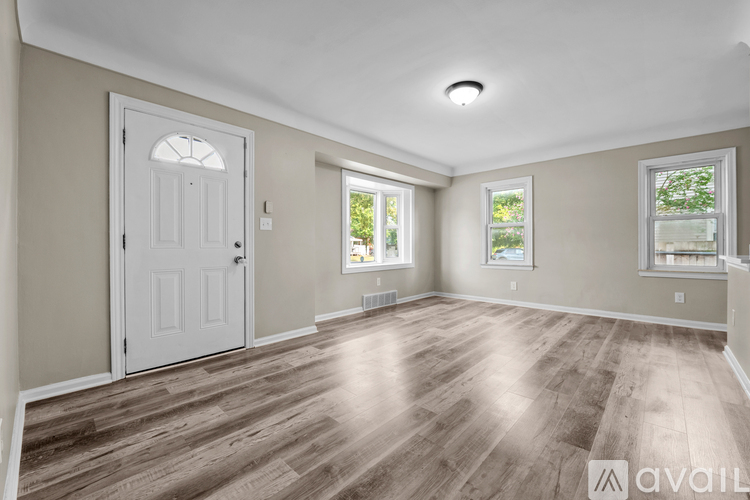 A spacious room with wooden flooring and a white door.