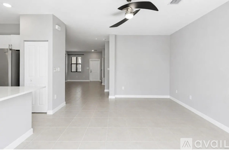 A spacious, empty room with a ceiling fan and tiled flooring.