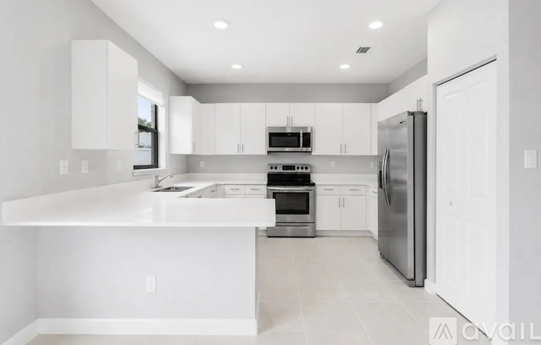 A modern kitchen with white cabinets and appliances.