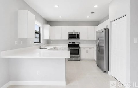 A modern kitchen with white cabinets and appliances.