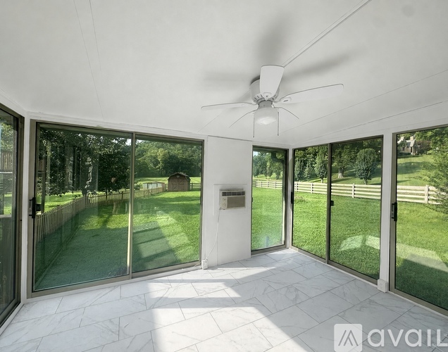 A sunny day in a spacious room with a ceiling fan and sliding glass doors.